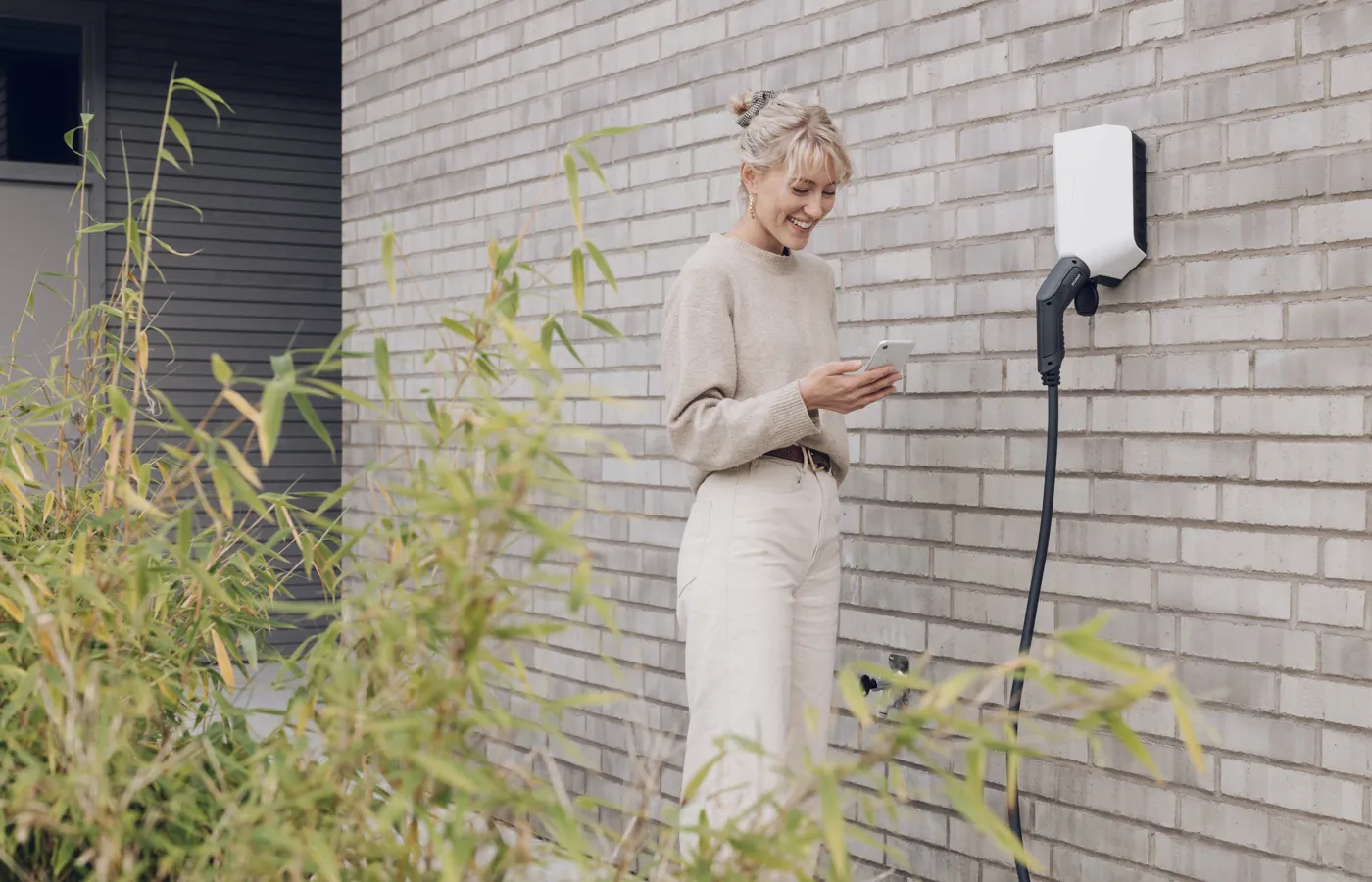 Kvinde der står ved en ladeboks til elbil